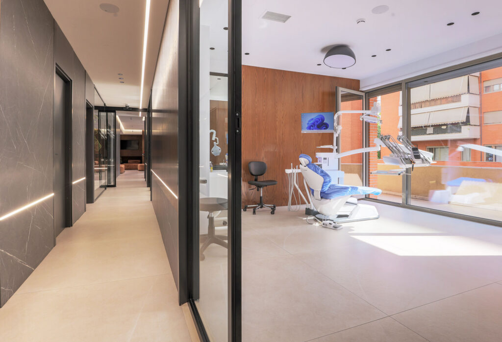 Pasillo luminoso y gabinete con paredes de cristal en la clínica dental Health Medical Center